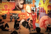 a group of people doing a dance in front of a mural