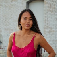 a woman in a pink dress posing in front of a brick wall