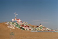 a cross painted on the side of a sand hill