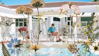 a woman sits on a bench next to a pool with flowers