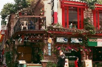 a woman is walking down the street in front of a restaurant