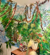 a room with a mural of tropical plants and trees