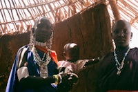 two women and a child standing in front of a hut